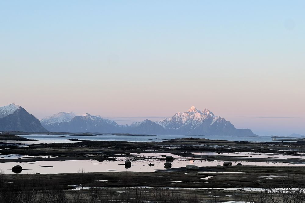 Fjelltopp med rosa morgenlys over fjæra